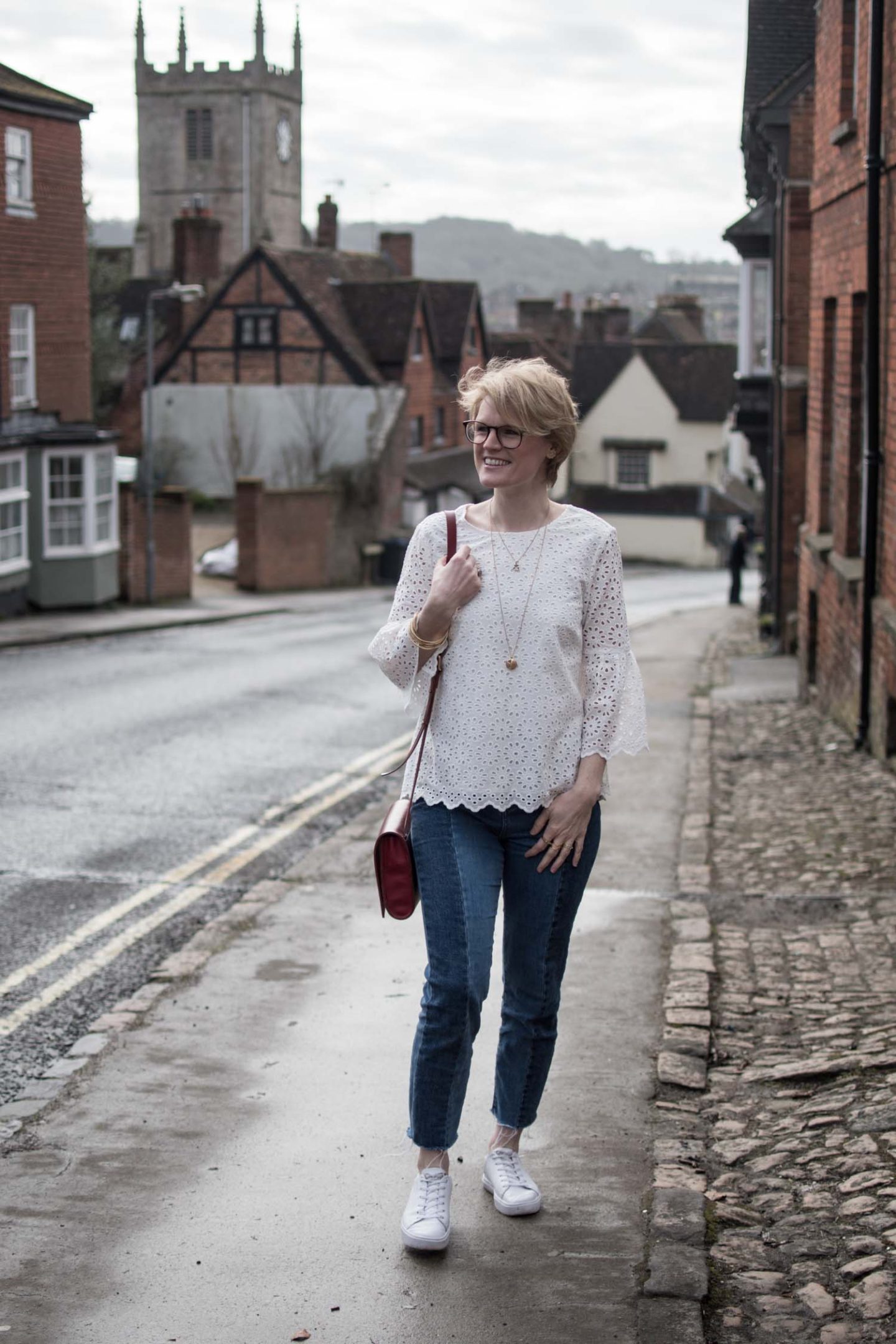 Sustainable style blogger Karen Maurice of n4mummy wearing a white embroidered top from Thought, jeans, trainers and a red bag