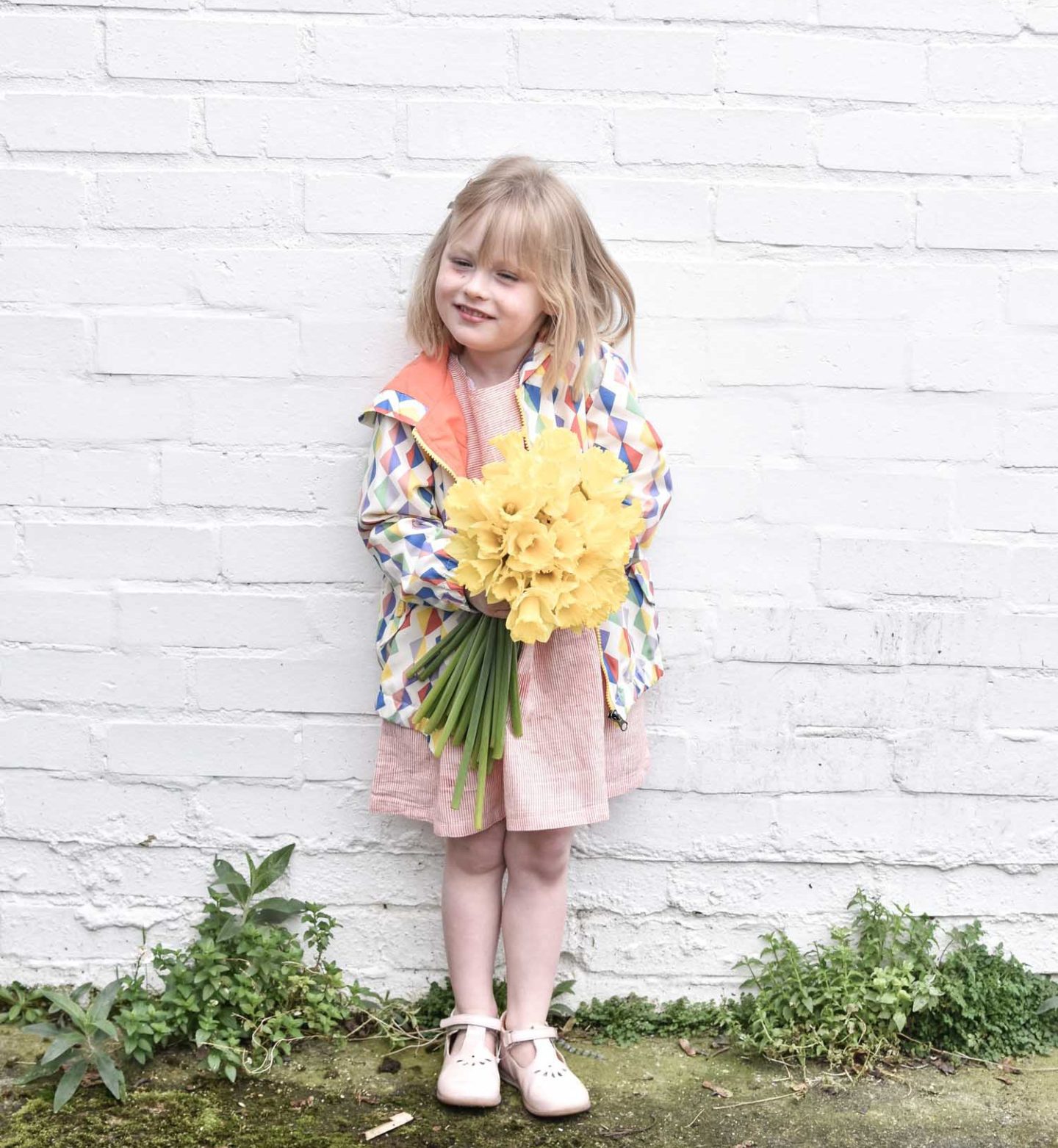 Daisy wears a smock dress and diamond print rain coat from Tootsa MacGinty