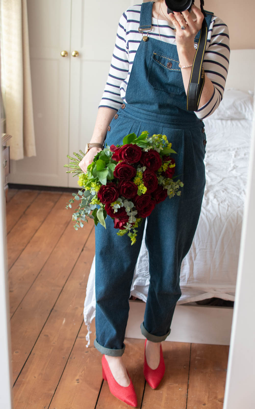 Karen Maurice of n4mummy in a striped jumper and dungarees with a bunch of red rose