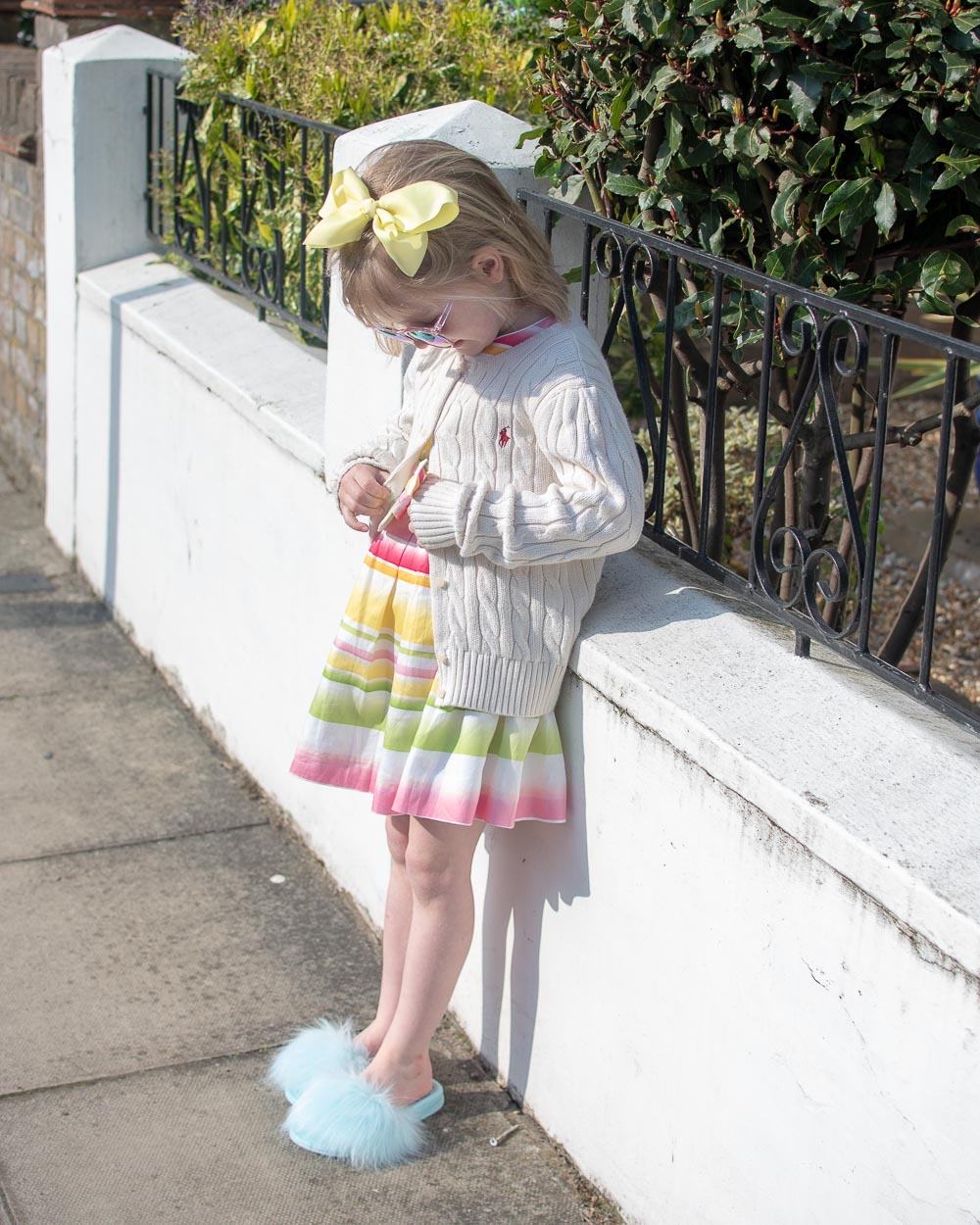 Daisy wearing second hand children's clothing from Slof, stripe dress, fluffy slides and a Ralph Lauren cardi