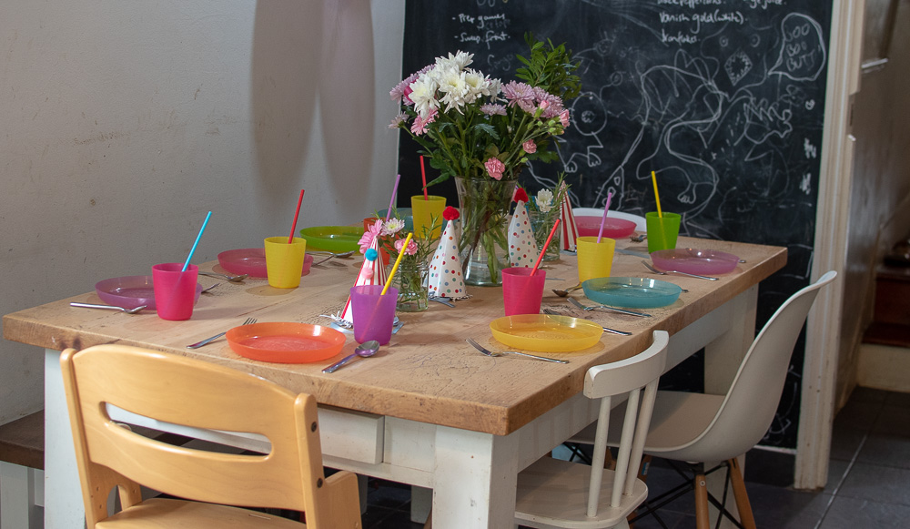 A zero waste party table, reusable plates and cutlery, flowers for decorations and paper straws