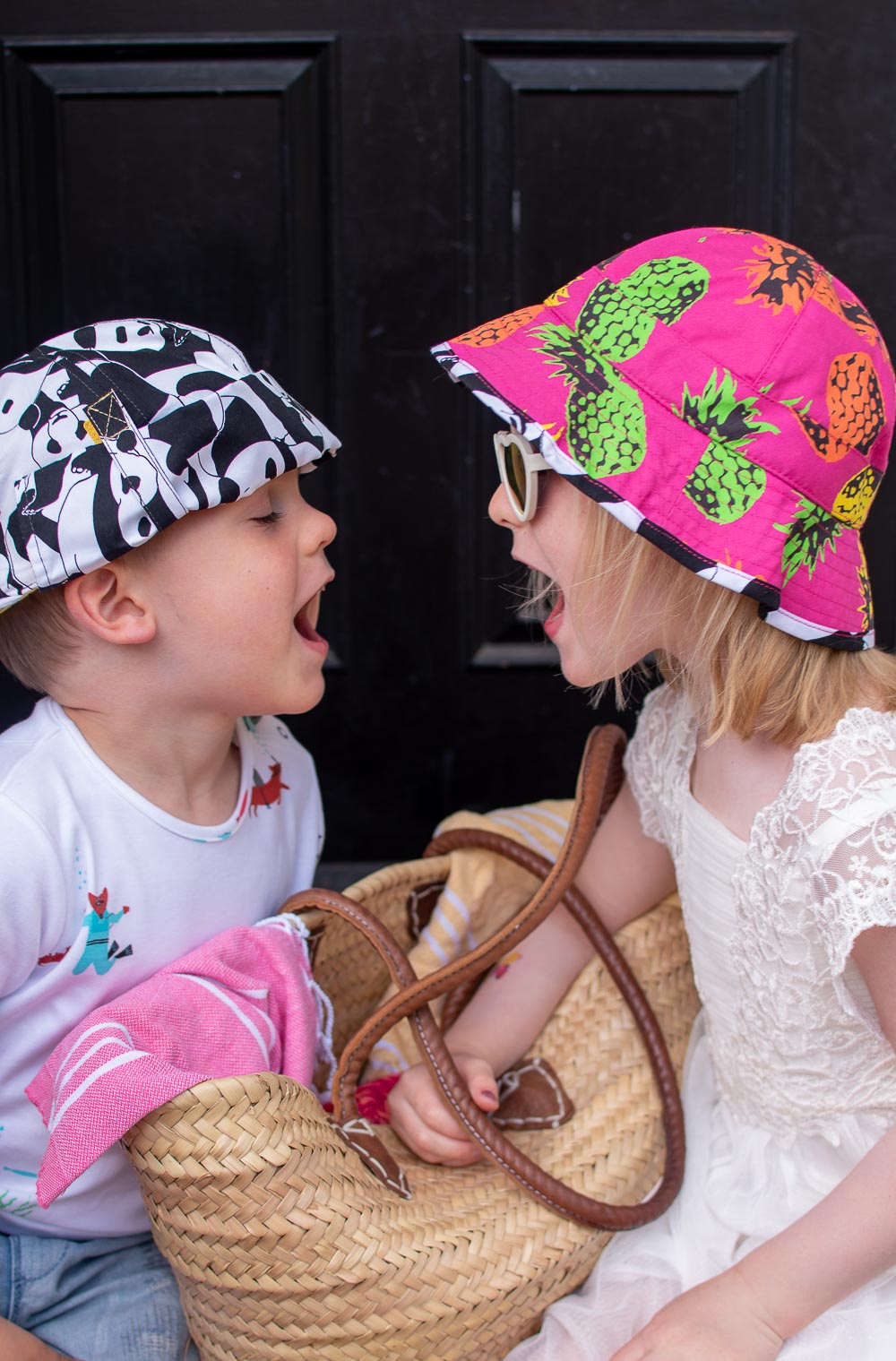 Daisy and Laurie holiday ready in their preloved children's clothes from Loopster. Daisy wears a white dress with printed hat and sunglasses and Laurie an underwater themed T Shirt with jean shorts and a print hat.