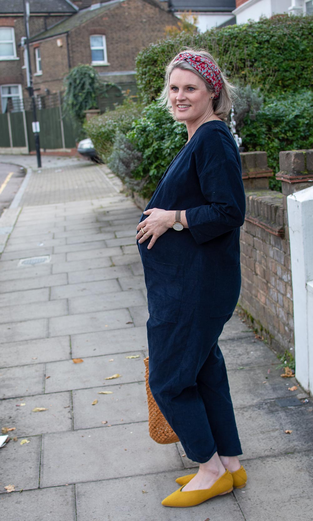 Karen Maurice of n4mummy wearing ethical maternity clothes from Clary & Peg. A organic blue boiler suit with a floral headband and yellow shoes