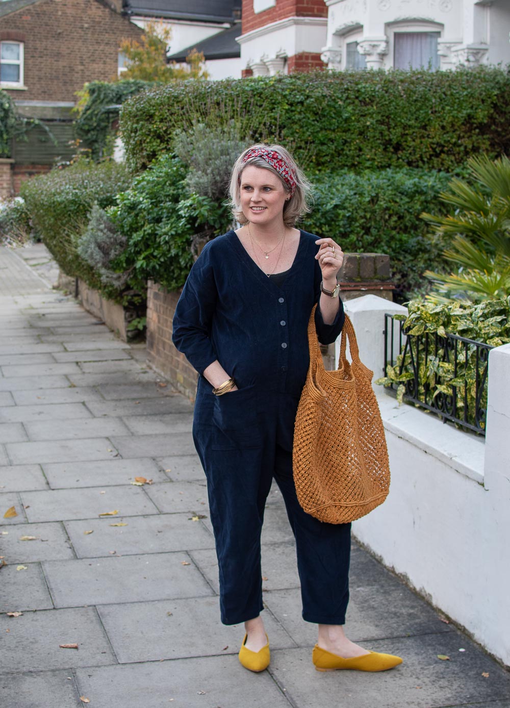 Karen Maurice of n4mummy wearing ethical maternity clothes from Clary & Peg. A organic blue boiler suit with a floral headband and yellow shoes