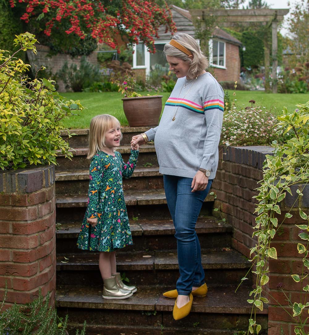 Karen Maurice of n4mummy wearing a rainbow stripped maternity jumper from Frugi and skinny maternity jeans from Jo Jo Mamam Bebe with her daughter in a skater dress all from Frugi. Ethical Maternity Clothes