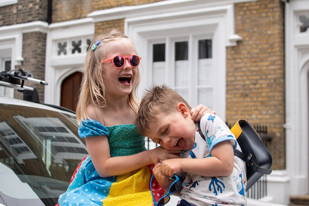 Daisy and Laurie sitting on top of a BMW hybrid car