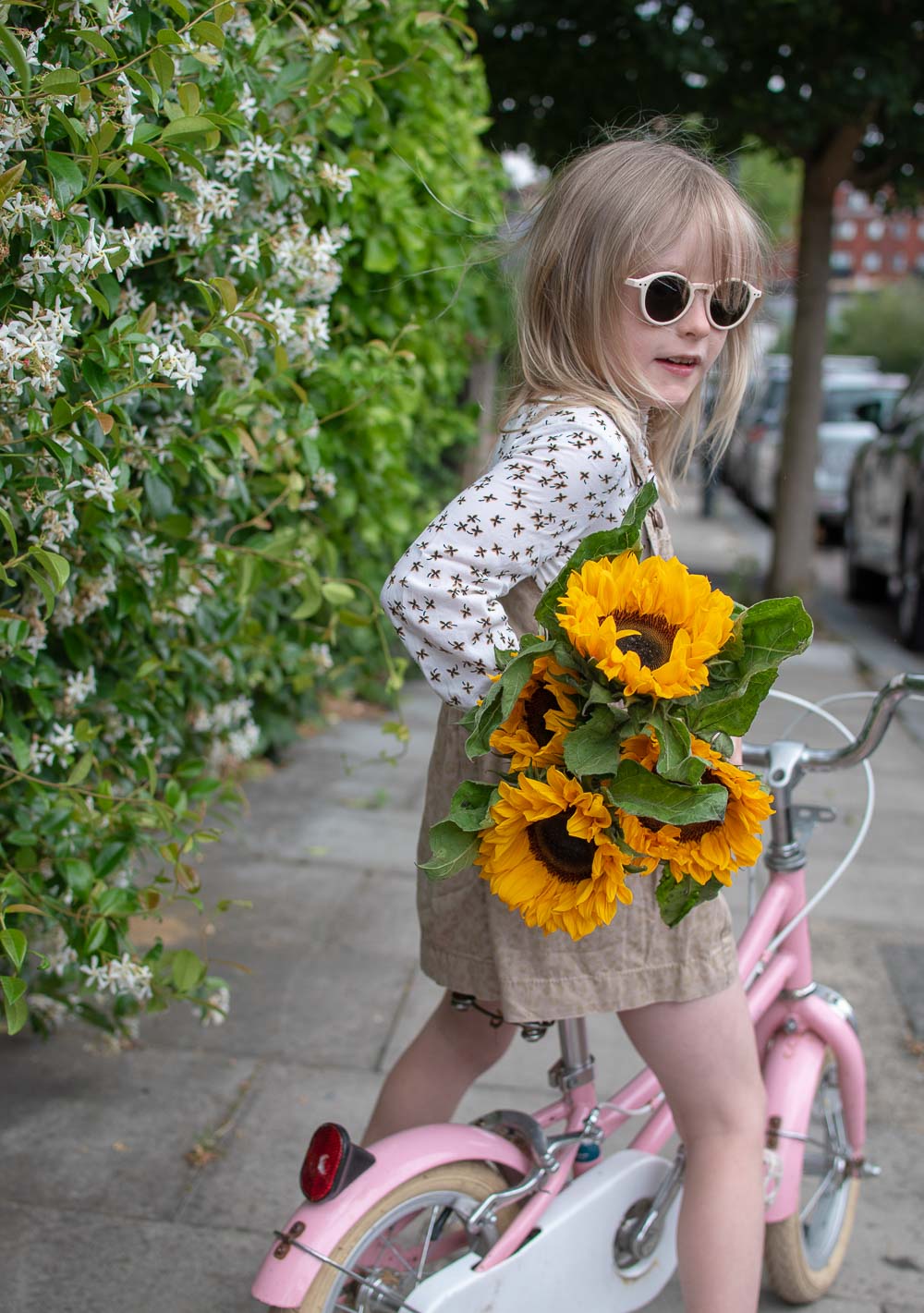 OshKosh pinafore dress and floral skirt worn by a young girl, from second hand clothing brand Tot Swap