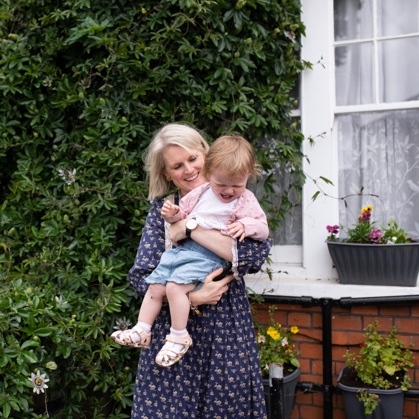 sustainable influencer Karen Maurice of n4mummy with her child, outside a pretty house with flowers